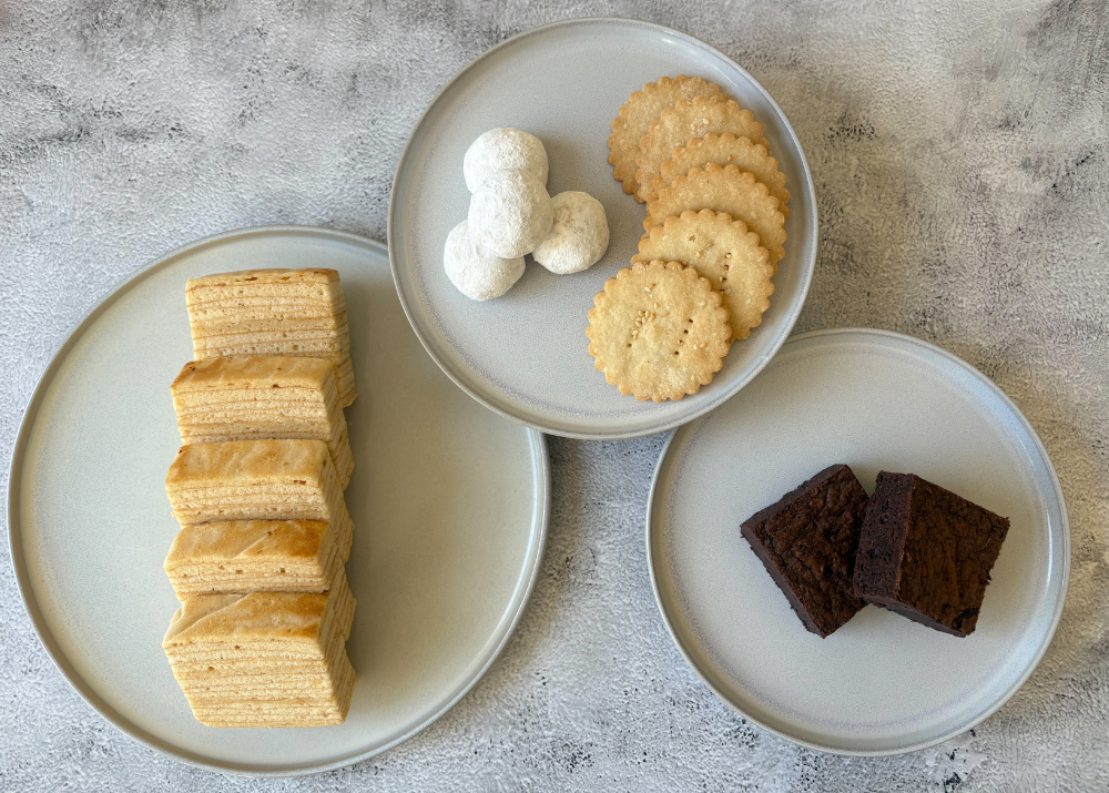 Three Sweet Labo plates with different types of cookies on a gray surface